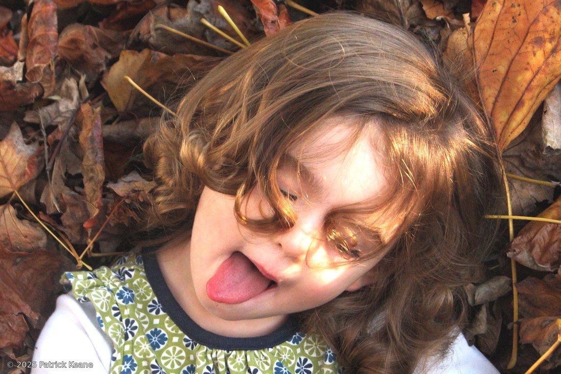 A child laughing in a pile of autumn leaves